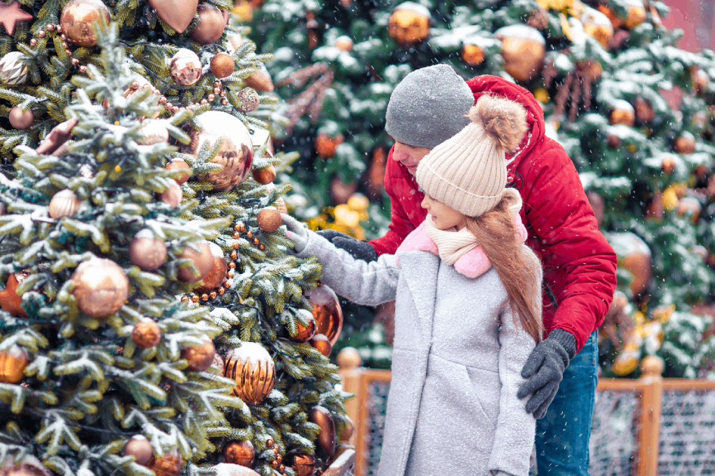 Père et fille profitant de la magie de Noël en observant les décorations d'un arbre de Noël sous la neige